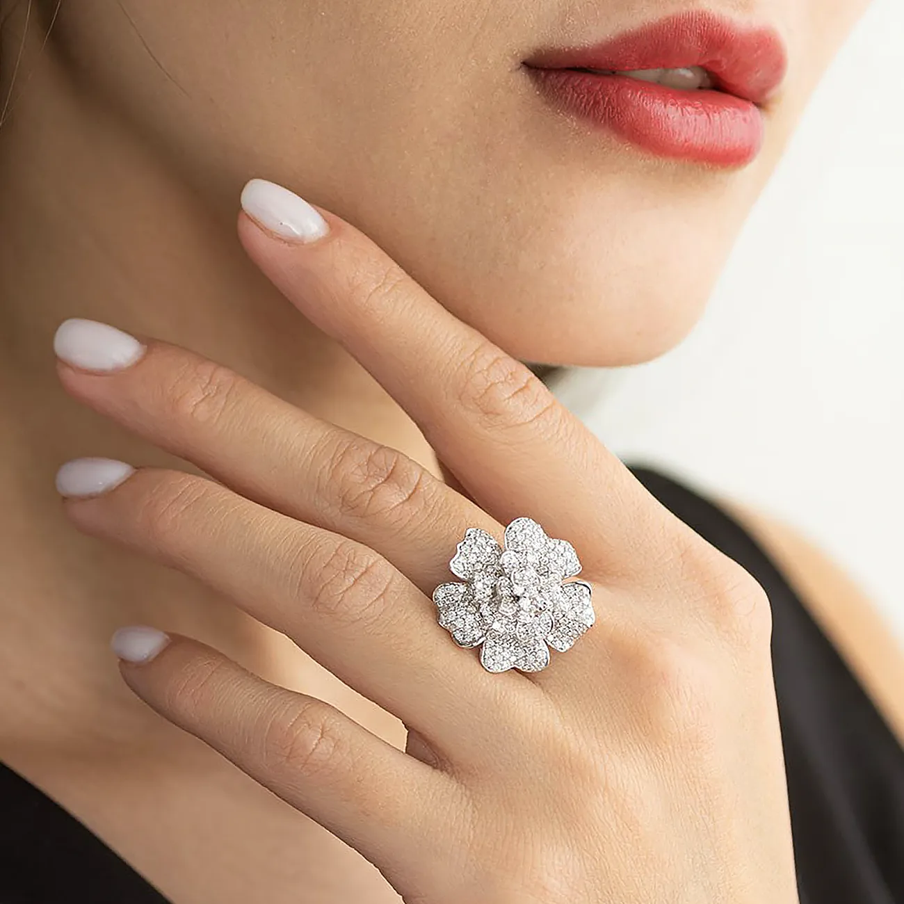 Bespoke white gold flower ring with clear diamonds is worn on a woman's finger