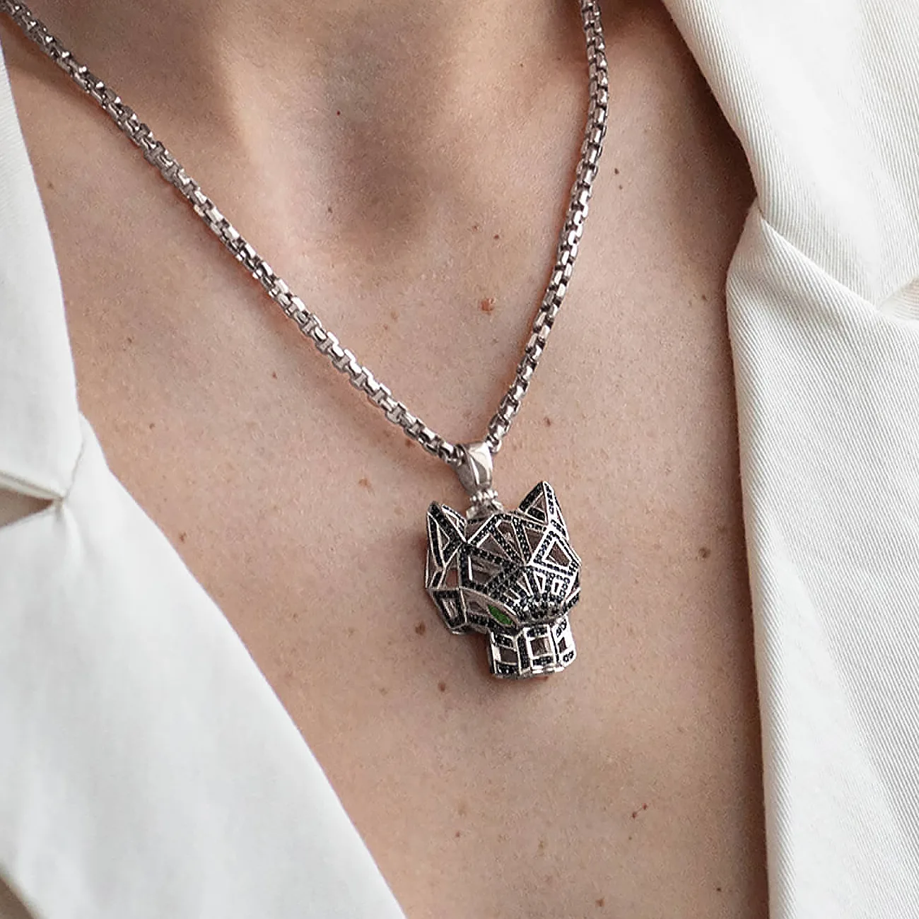 Custom white gold tiger pendant with black diamonds and emerald eyes is worn by a woman